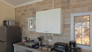 Una cocina equipada con microondas, refrigerador, armarios, un escurreplatos, estufa a gas y cafetera.