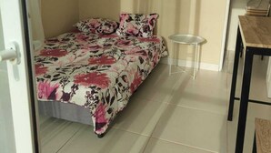 Un dormitorio con una cama, una mesita y una silla.