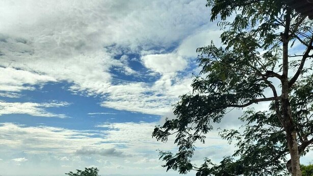 Terraza de madera con mobiliario exterior, barandilla y vistas a un paisaje montañoso.