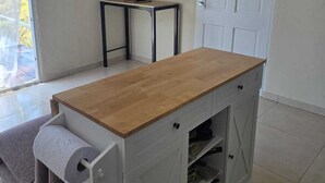 Una habitación con una mesa de madera, un televisor montado en la pared, una puerta y una mesita con un rollo de papel higiénico.