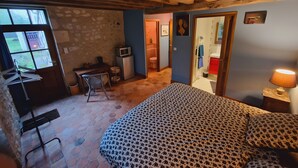 Un dormitorio con una cama, un escritorio, una silla, un televisor y una lámpara.