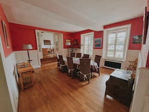 A dining area with a wooden table and chairs, a lamp, and a view of the outside through a window.
