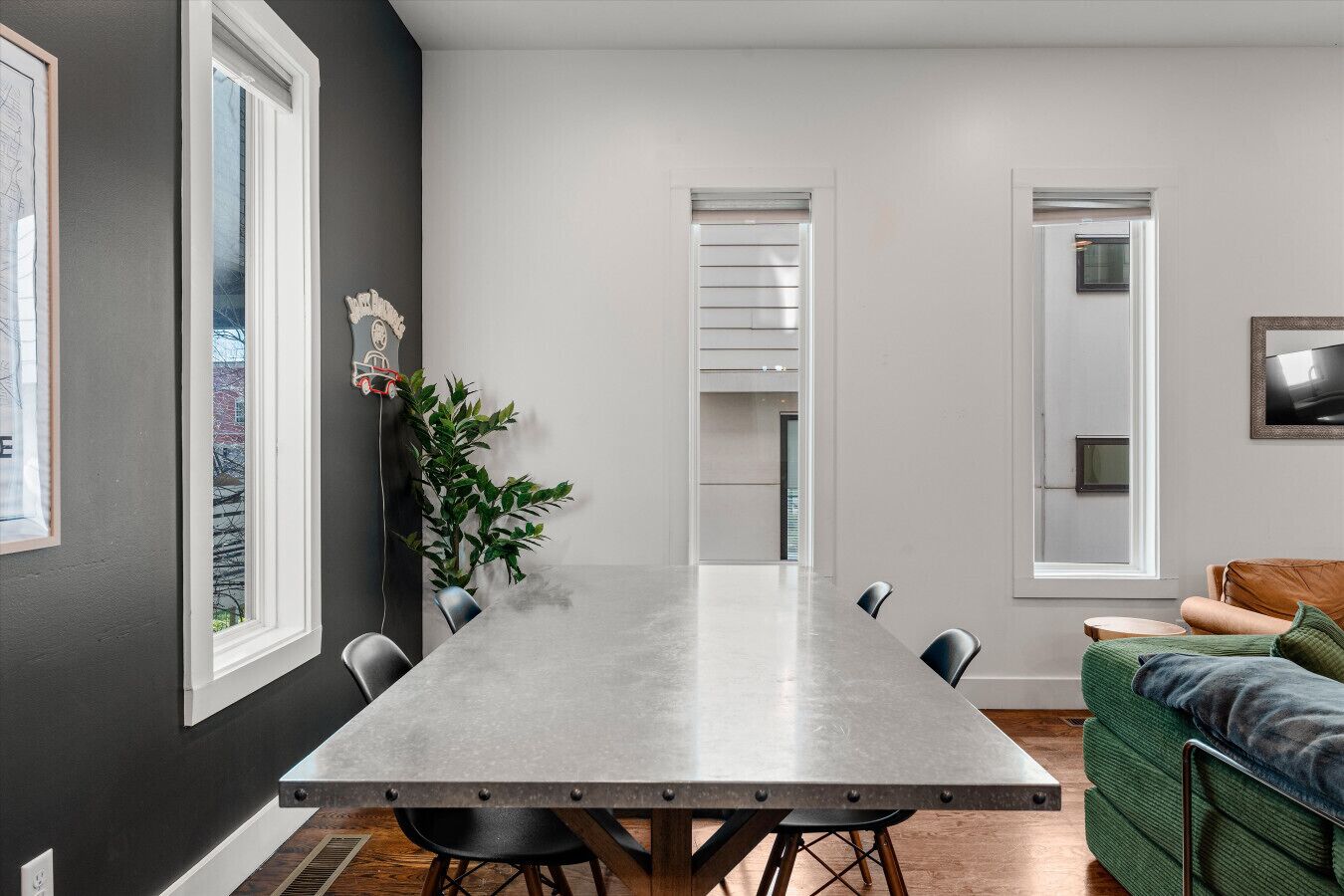 Un espace repas moderne avec une longue table, des chaises et un canapé vert.
