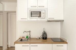 Een keuken met een magnetron, spoelbak, waterkoker en een houten aanrecht.