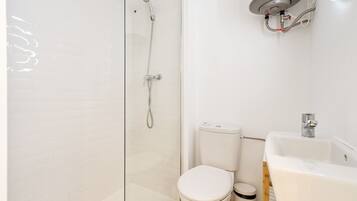 Un baño con ducha de vidrio, inodoro y lavamanos.