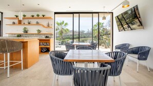 A modern kitchen with a dining area, large windows, and a view of the outdoors. - Condo with Arco views, infinity pool, and spa (Cabo San Lucas)