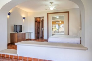 Ein Hotelzimmer mit Bett, Fernseher, kleinem Tisch und Blick nach draußen.