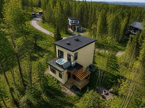 A modern two-story cabin with a rooftop pool, surrounded by dense forest.