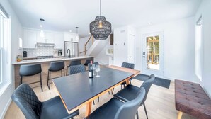 A modern kitchen with white cabinets, a black dining table, and black chairs. - Spa & Nature Escape | Le Nova (Adstock)