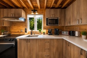 A modern kitchen with wooden cabinets, a stainless steel range, a microwave, and a coffee maker.