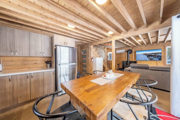 A wooden interior with a kitchen, dining area, and a large window with a view.