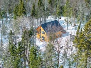 A cabin surrounded by trees in a snowy landscape.