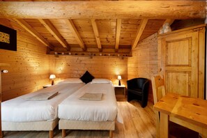 Ein Holzhütten-Zimmer mit zwei Betten, einem Tisch und einem Stuhl.