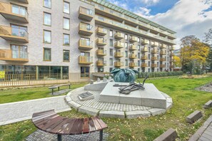 A multi-story building with balconies, a paved courtyard, and a sculpture. - Comfortable Apartment | View Terrace (Wrocław)