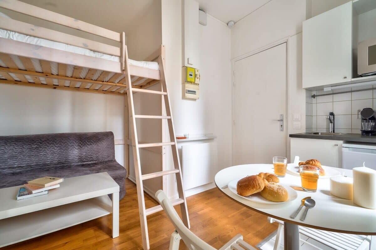 A bunk bed, a sofa, a table with food and drinks, and a kitchen area.
