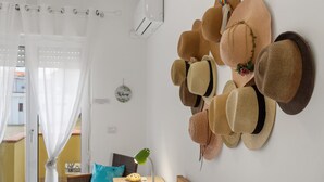 Una habitación con una colección de sombreros en la pared, un escritorio con una lámpara y vistas a través de un ventanal.