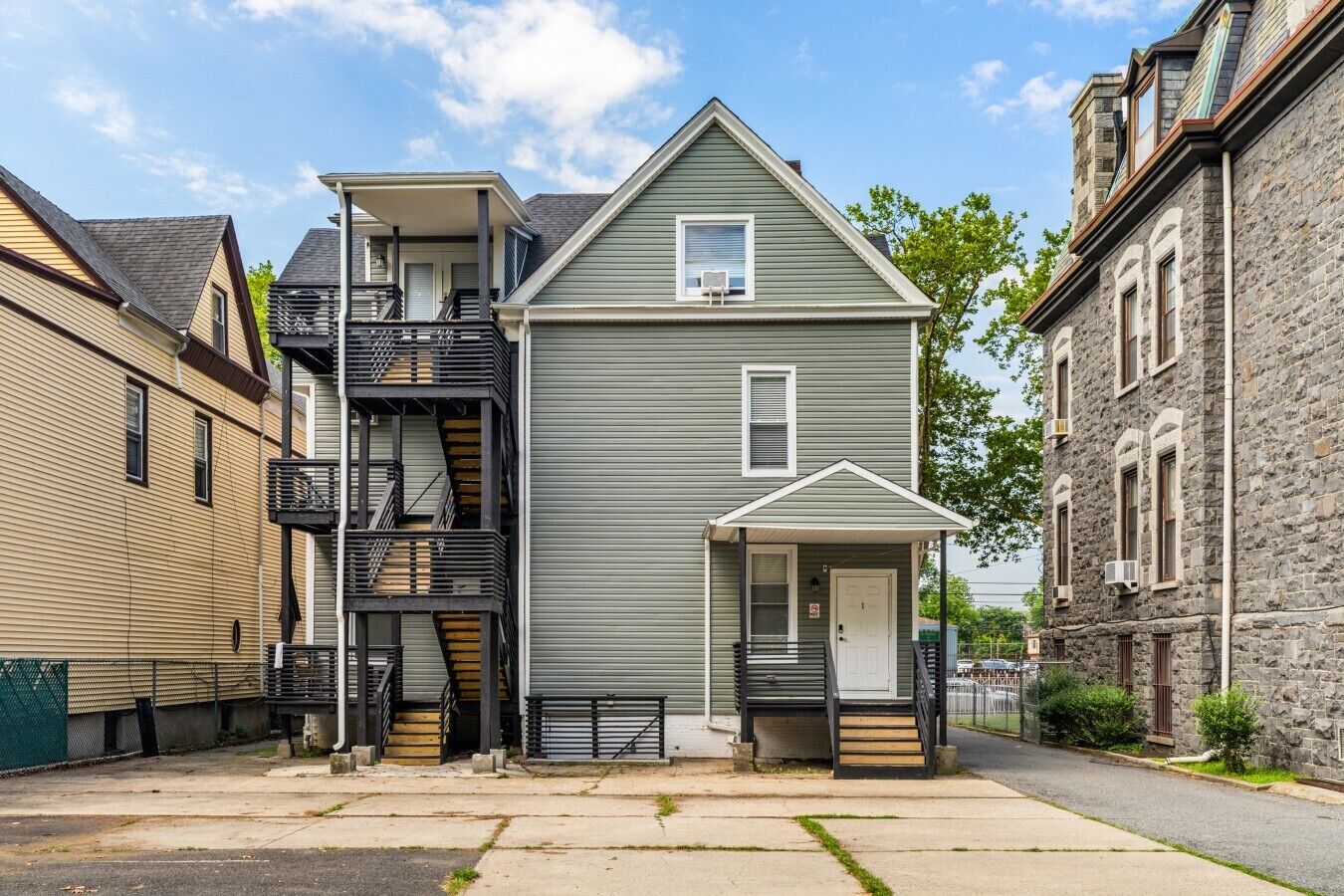 A two-story residential building with a front porch, a visible staircase, and a small attached garage.
