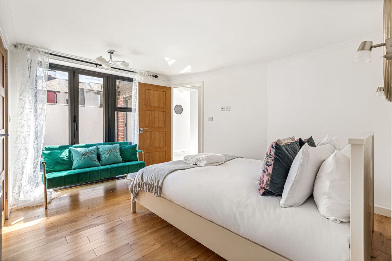 Ein Schlafzimmer mit einem Bett, einer grünen Couch und Holzboden.