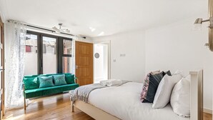 A bedroom with a bed, a green sofa, and a wooden floor. - Pear Tree Cottage - pet friendly (Oxfordshire)