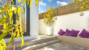 A modern outdoor seating area with steps leading up to a white wall, a potted plant, and a wooden fence. - Pear Tree Cottage - pet friendly (Oxfordshire)