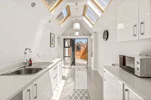 A modern kitchen with skylights, a sink, a microwave, and a view to the outside. - Pear Tree Cottage - pet friendly (Oxfordshire)