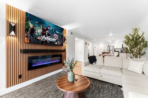 Una sala de estar moderna con un televisor de pantalla plana, chimenea, sofá y zona de comedor.