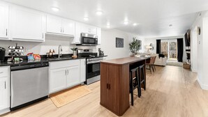 Een moderne keuken met witte kasten, roestvrijstalen apparatuur en een houten kookeiland.