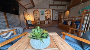 A cozy living area with a wooden table, two sofas, a brick wall, and a small seating area with a bench and chairs. - Lake Retreat - Private Dock • Hot Tub • Arcade • Pickleball • Basketball (Gobles)