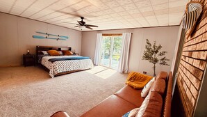 Une chambre avec un lit, un canapé, un ventilateur de plafond et une vue sur l’extérieur.