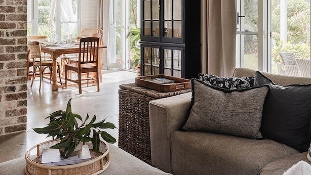 A cozy living area with a sofa, a dining table with chairs, a wicker basket, and a large window with curtains. - Scribbly Gums Berrara (Berrara)