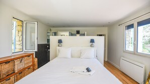 Ein Schlafzimmer mit einem Bett, Nachttischlampen, einem Schminktisch und einem Fenster.