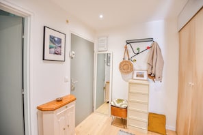 Ein Flur mit einem Holzschrank, einem kleinen Hocker, einem an der Wand befestigten Kleiderständer und einem gerahmten Bild.