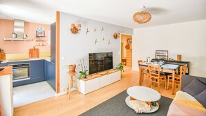 En moderne stue med TV, sofa, spisebord og et køkkenområde.