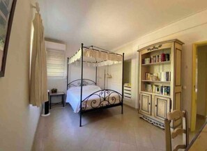 A bedroom with a four-poster bed, a bedside table, a bookshelf, and a chair. - Beautiful 3 bed villa with pool - Alto Golf & Country Club, Alvor (Alvor)