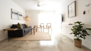 Uma sala de estar moderna com um sofá, poltronas, uma mesa de centro e uma planta grande.