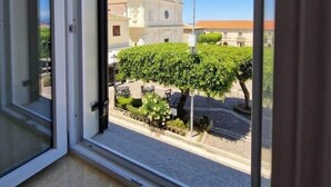 A window with a view of a building with two domes and a courtyard with plants.
