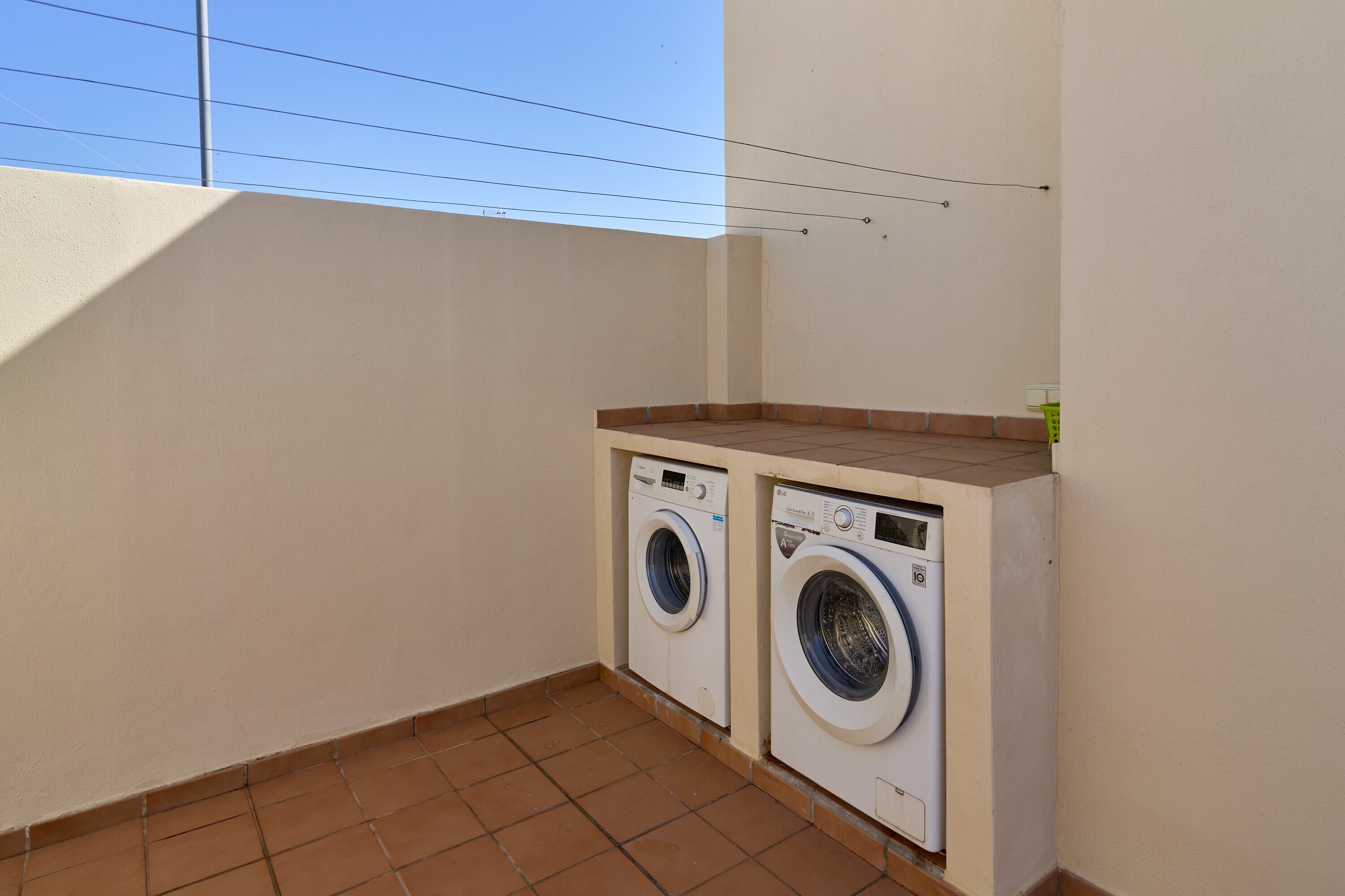A laundry room with two washing machines, a tiled floor, and a sloped ceiling.