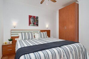 Ein Schlafzimmer mit einem Bett, einem Nachttisch aus Holz, Wandleuchten und einem großen Holzschrank.