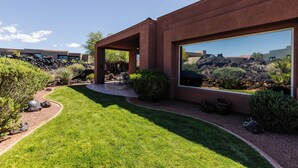 Una casa moderna con un patio, un ventanal grande y un jardín bien cuidado.