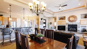 Una amplia sala de estar con chimenea, un comedor con mesa y sillas de madera, y una cocina con alacenas de madera y horno empotrado.