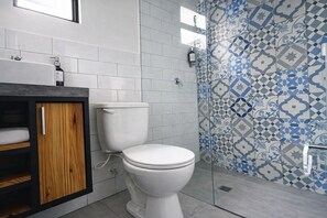 A bathroom with a white toilet, a wooden cabinet, and a tiled shower area. - Cozy loft in Laureles (Medellín)