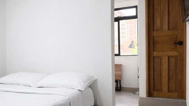 Un dormitorio con cama, una puerta de madera y una ventana.