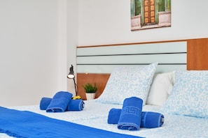 Ein Hotelzimmer mit einem Bett, blauen Handtüchern, einem Nachttisch mit Lampe und einem kleinen Topfpflanzen.