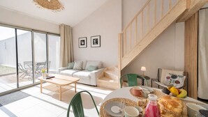 Een moderne woonkamer met een bank, salontafel en een eethoek met een fruitschaal.