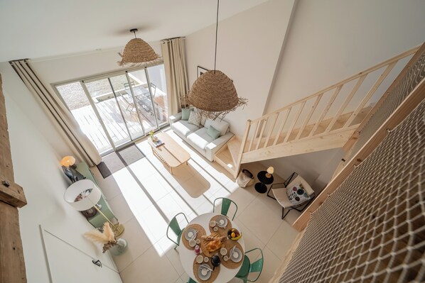 A modern interior with a dining area, a sofa, and a staircase.