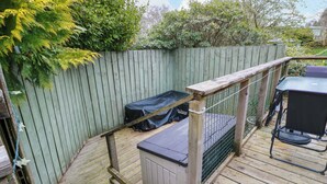 Eine Holzterrasse mit Metallgeländer, einem überdachten Stauraum und einem Grillbereich.