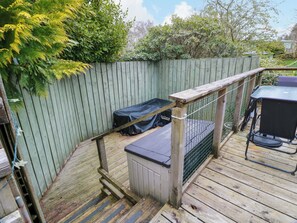 A wooden deck with a metal railing, a covered storage unit, and a grill area. - L21 Coastal Kippford (Dalbeattie)