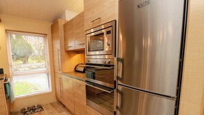 A compact kitchen with a stainless steel refrigerator, oven, and microwave. - L21 Coastal Kippford (Dalbeattie)