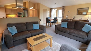 A modern living room with two sofas, a coffee table, and a dining area with a table and chairs. - L21 Coastal Kippford (Dalbeattie)