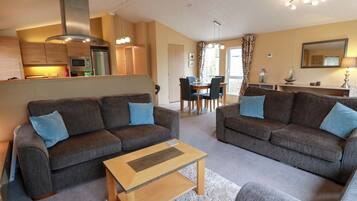 A modern living room with two sofas, a coffee table, and a dining area with a table and chairs.